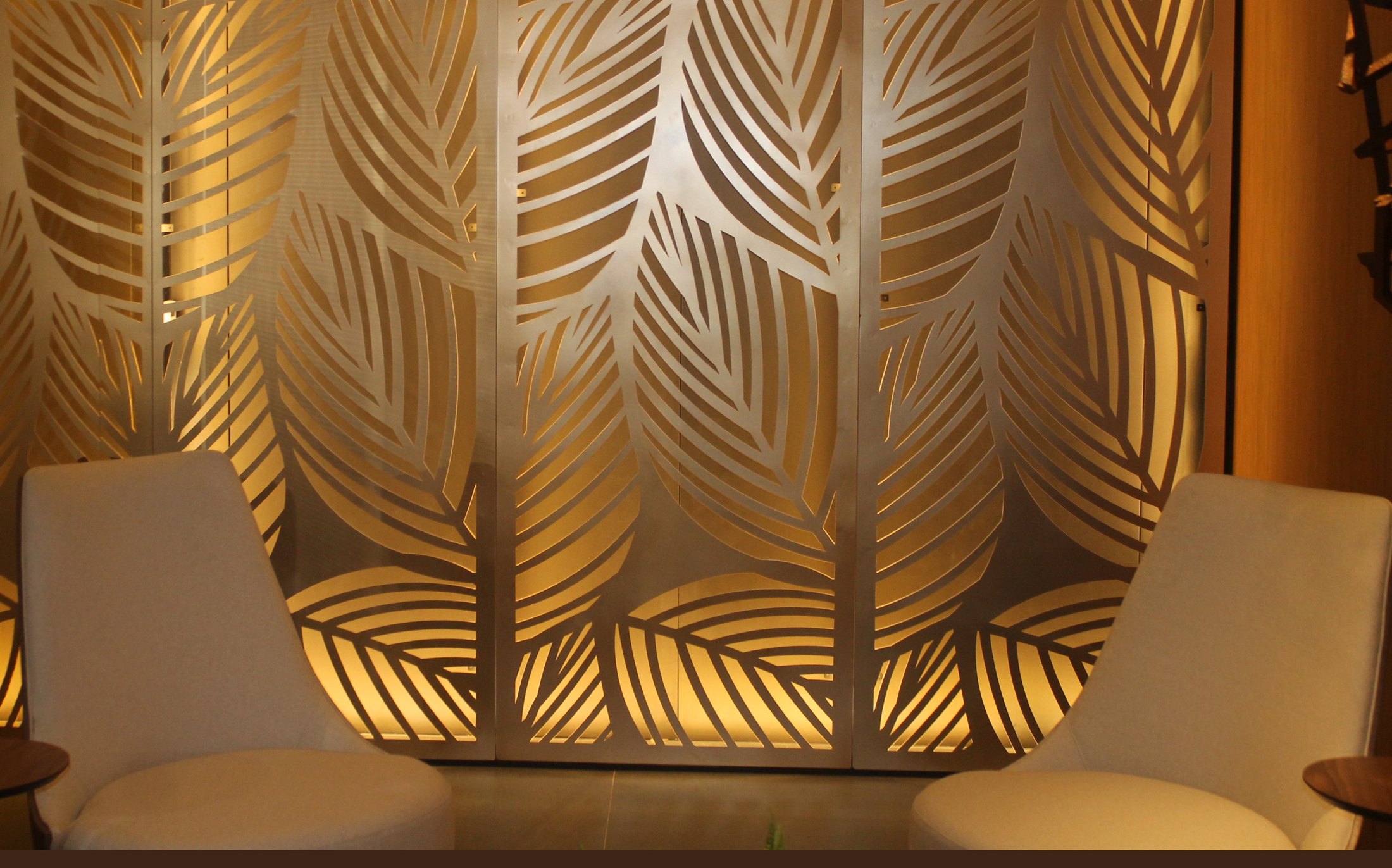 Painel dourado de folhas vazado a laser com poltronas