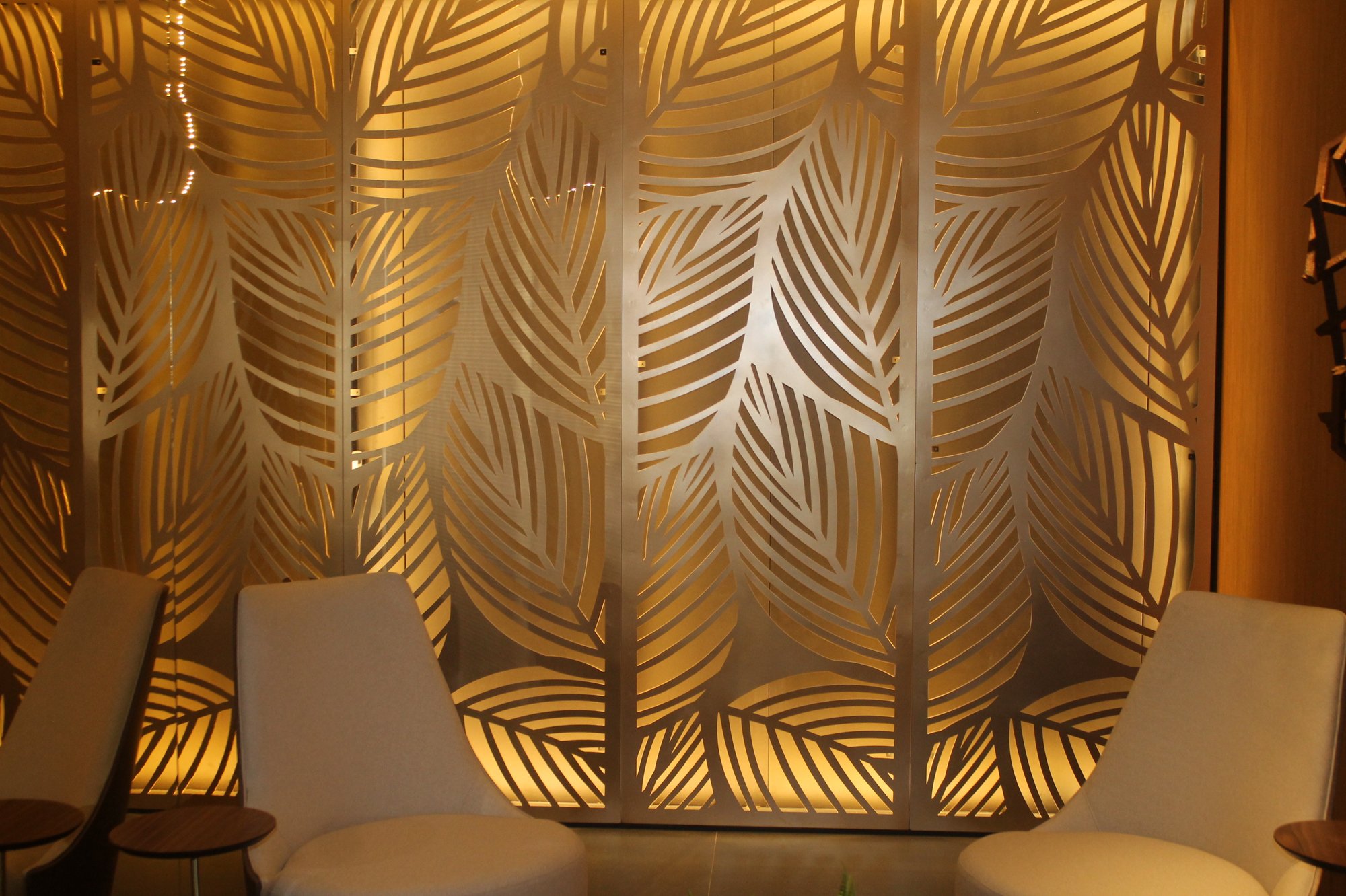 Painel metálico dourado com padrão de folhas vazado a laser